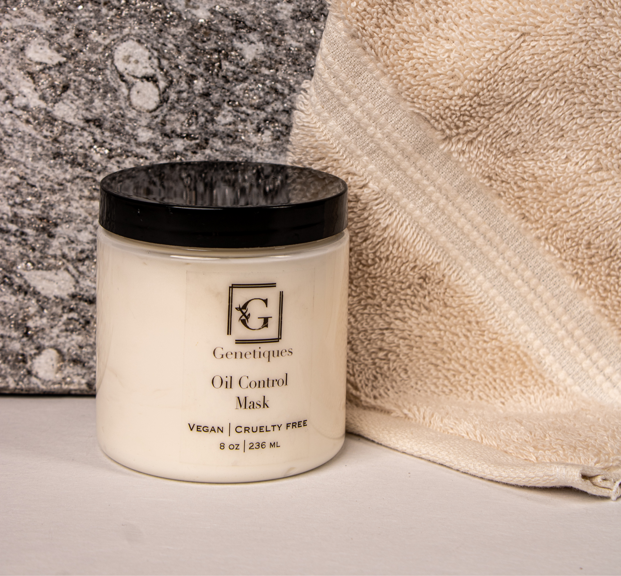 Genetiques Oil Control Mask Vegan Cruelty Free standing next to a towel and stone.