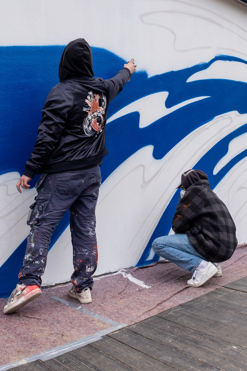 Zwei Personen malen ein Graffiti Kunstwerk, sie malen abstrakte Formen, Wien