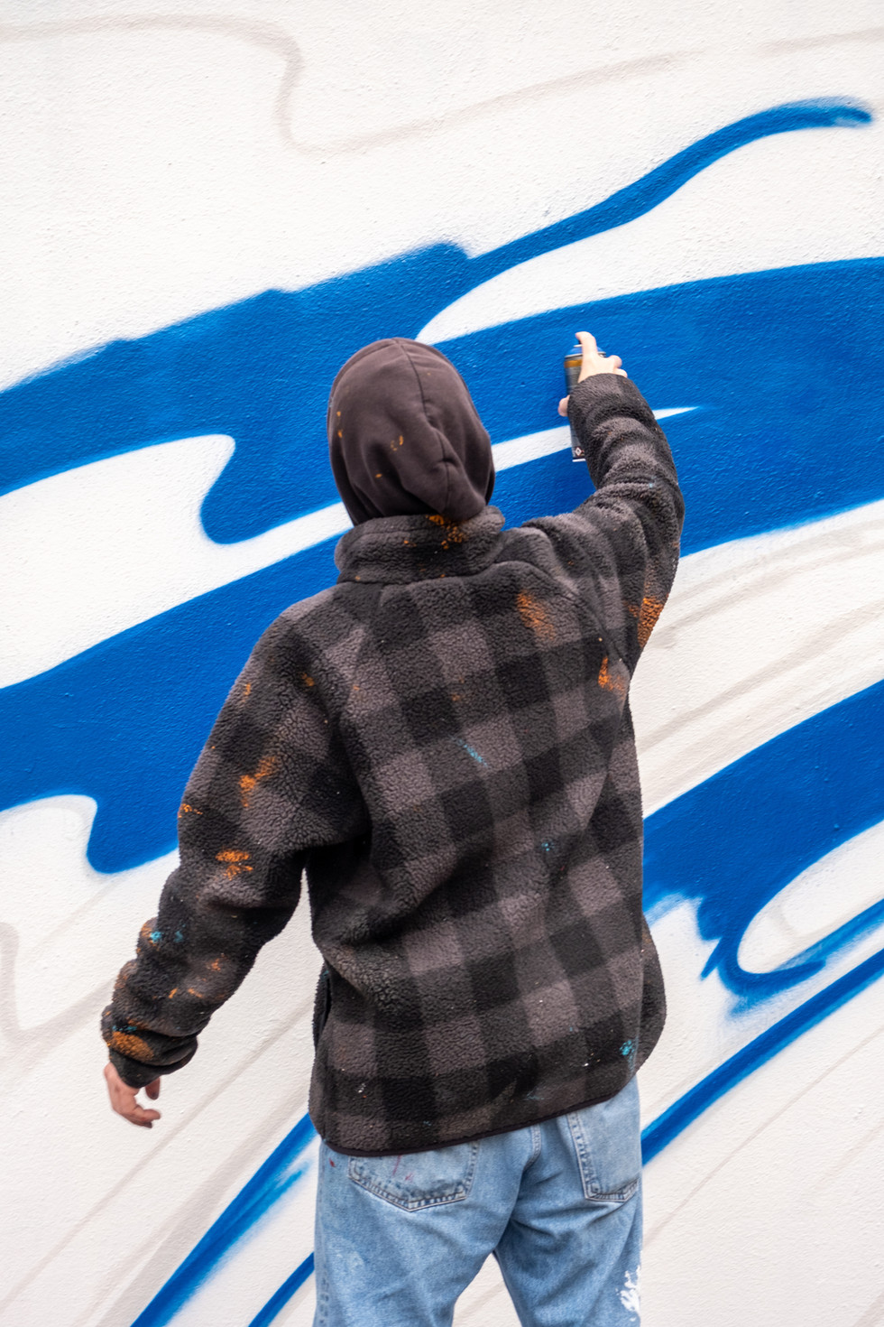 Eine Person sprüht ein Graffiti Wandbild, blau Farben, Wien