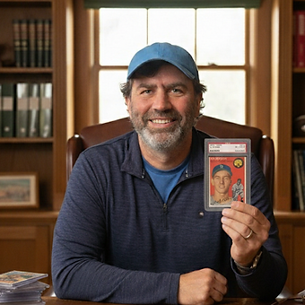 Isaac Hillson, owner of Golden Era Cards, at his desk holding a graded Al Kaline rookie card.
