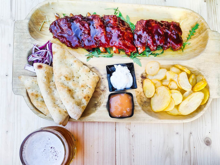 Coaste de porc BBQ servite cu cartofi, lipie și sosuri în restaurantul Complexului MAX International din Râșnov.