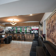 Bar de lobby cu tejghea din lemn, fotolii negre din piele și fresce murale, la Max Internațional Râșnov