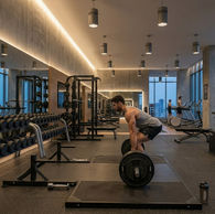 Barbat facand deadlift intr-o sala de fitness moderna cu ferestre panoramice si echipament