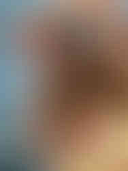 A woman holding up sunscreen at the beach, showcasing natural beauty in a  lifestyle setting.