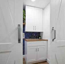 Bathroom with white vanity, blue tiles, seen through barn doors