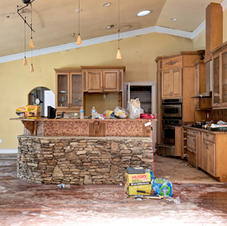 Kitchen with flood damage, wet floor, and cleanup supplies
