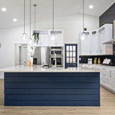 Modern kitchen with navy island, white cabinets, wood floor