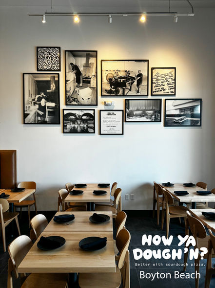 Custom framed black-and-white photography gallery wall installed inside a restaurant dining room in Boynton Beach, Florida.