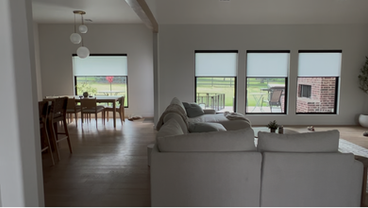 Living room with large sectional and white roller shades with black cassette and hem bar
