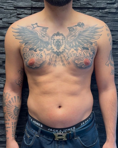 Tatouage d‘ailes sur le torse avec des clés sous les clavicules, un visage d‘ours sur le sternum et des écritures "Genesis", le tout entouré d‘ombrages