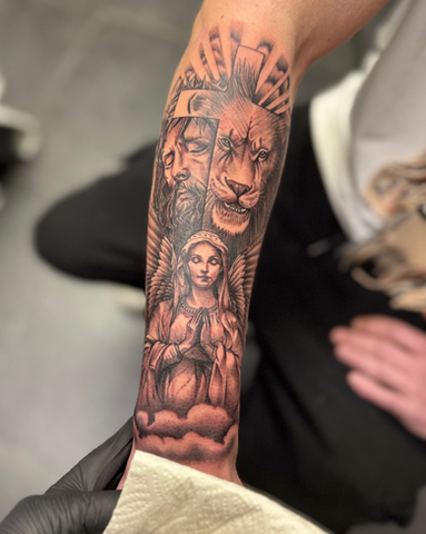 Tatouage réaliste sur le bras d'un ange, un lion et Jésus entourés de nuages