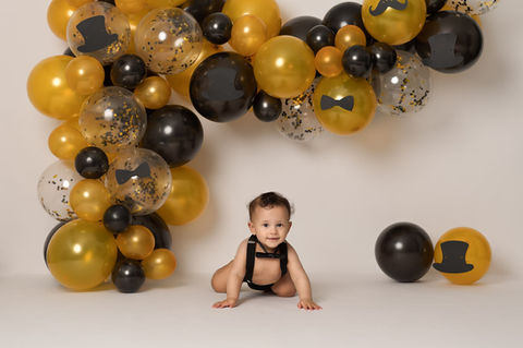 Black and gold balloon arch decoratinon for cake smash photoshoot