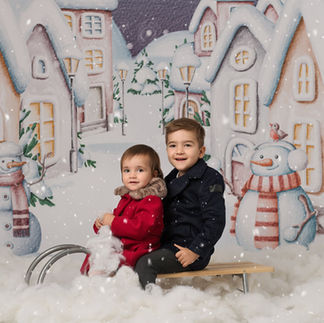 Siblings sitting on a sledge and smiling at their parents