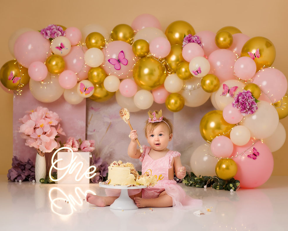 Girl hoilding a wooden spoon at her first cake smash session.