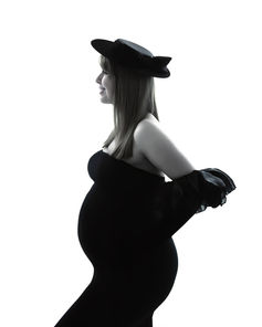 Black and white image of gorgeous pregnant woman wearing black hat, gloves and bodycon dress.