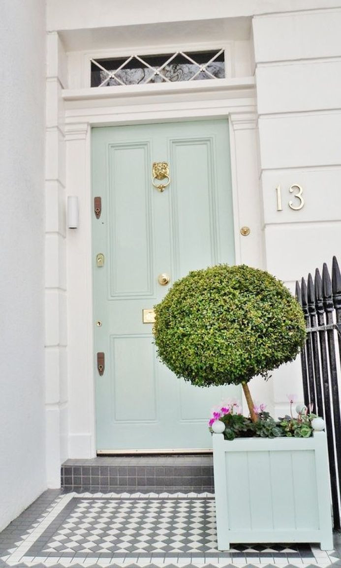 green and brass front door with lion knocker. Buxus in green trough. White house exterior. White house entryway | Pink flowers with mint green front door | Interior design studio | Interior design blog | Interior designer | What does your front door colour say about you
