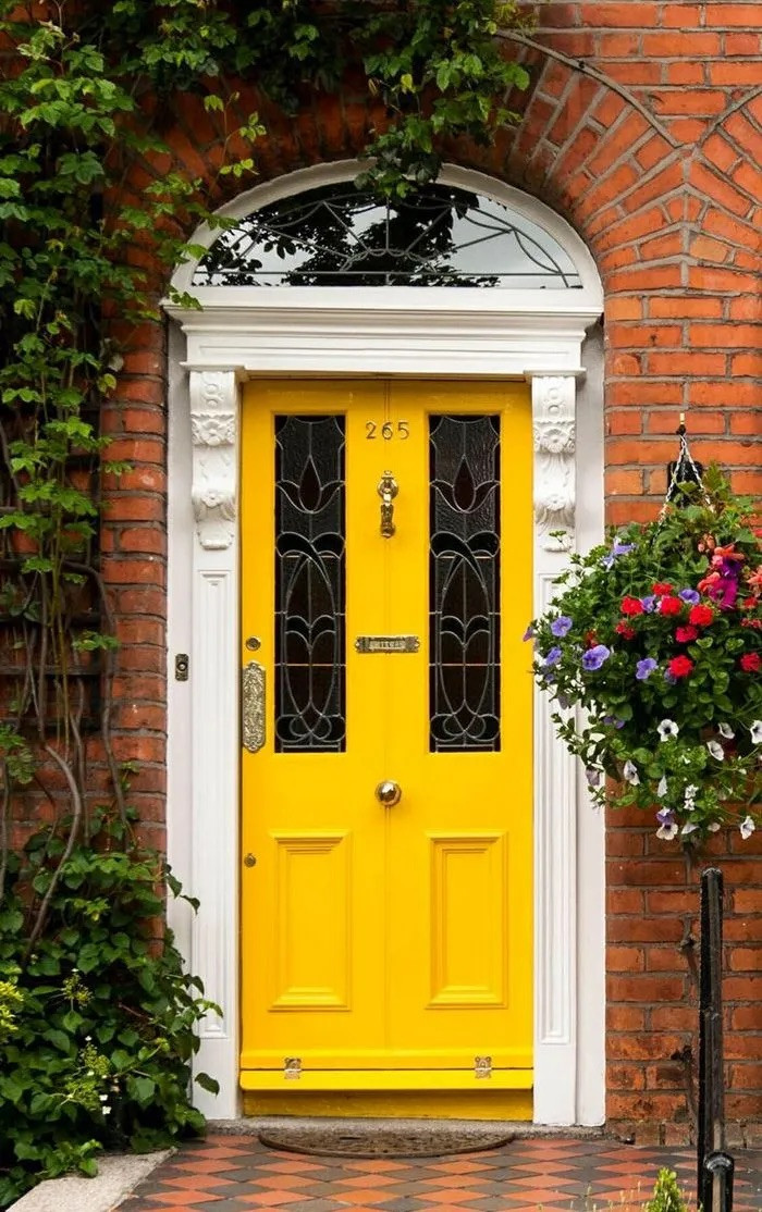 An eye-catching bright yellow makes this entrance feel inviting. Bright yellow door with brick exterior.