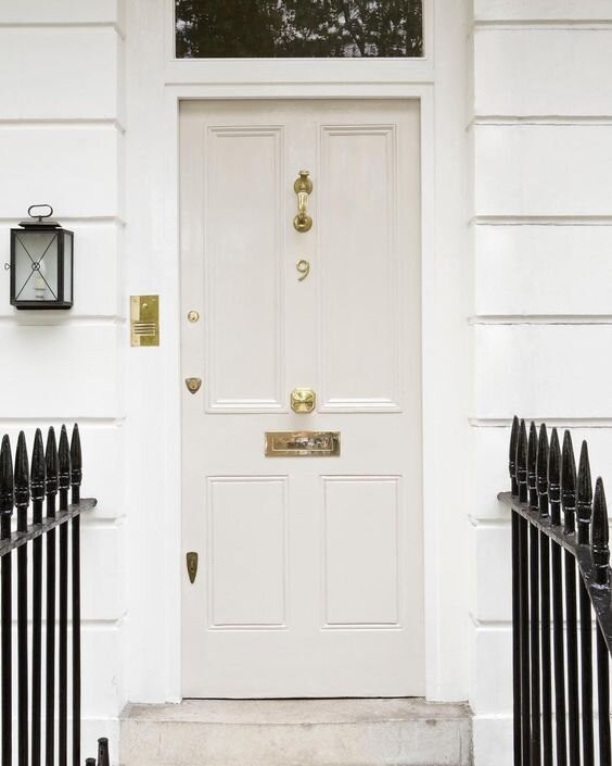 This white front door gives a sophisticated, traditional and subtle air. The contrast between the white facade of the house, the black wrought iron gates, the brass accessories and the off-white of the door exudes style