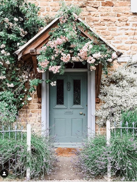 Cottage entrance. Green front door with wild roses over the porch. Lavender growing at the white fence Pink flowers with mint green front door | Interior design studio | Interior design blog | Interior designer | What does your front door colour say about you