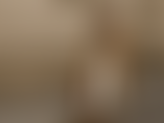 Mujer con pantalón blanco de invierno, abrigo camel, jersey gris y accesorios marrones caminando en una calle elegante.