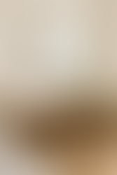 Espejos decorativos grandes con marco dorado en un salón moderno, reflejando ventana y sofá, sobre consola de madera con lámpara y planta decorativa.