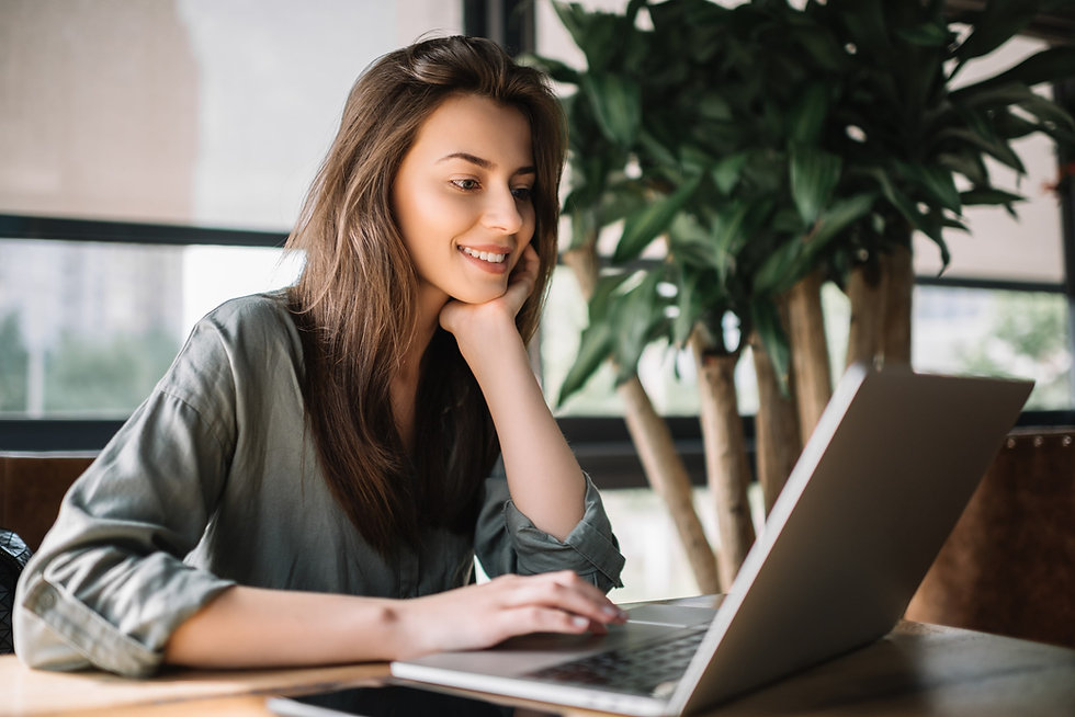 Young woman seated smiling using laptop computer
