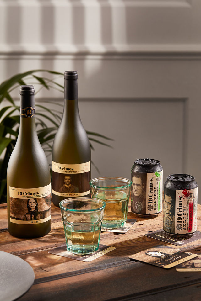 Wine bottles, cans, and glasses on wooden table.