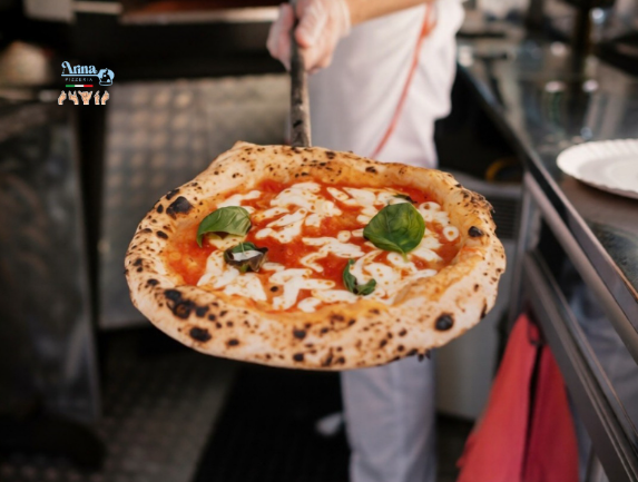Chef holding authentic Neapolitan pizza in Saudi Arabia with soft crust, tomato sauce, and fresh basil topping