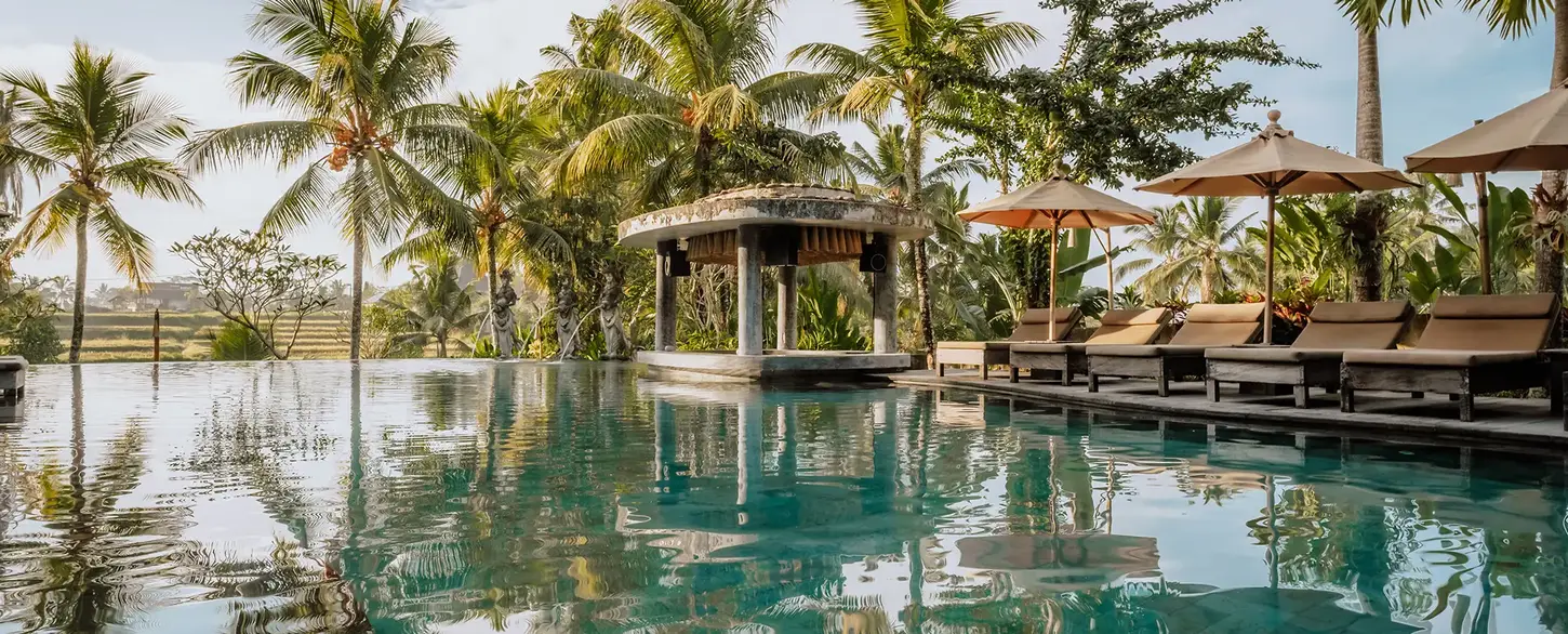 Hotel photographer, Bali | Hotel photography featuring the high-quality pool area of the 5-star Hotel Kuwarasan in Ubud, Bali, amidst palm trees and a tropical atmosphere.