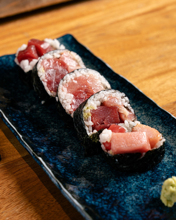 Rollos de sushi con atún fresco servidos en plato negro en Juniko restaurante.