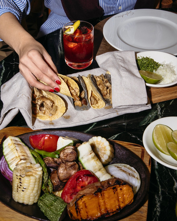 Mano sirviendo pan pita con bebida y guarniciones en Sylvestre Midtown