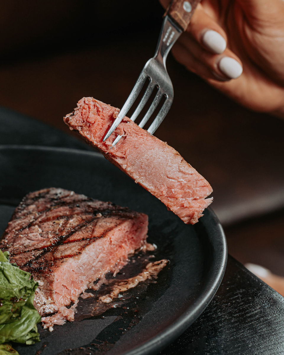 Corte de carne cocinado al grill servido en plato negro en Fuego Asador.