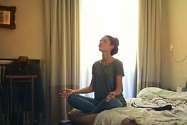 mulher fazendo meditação sentada em sua cama