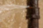Rusty burst pipe spraying water after freezing in winter.