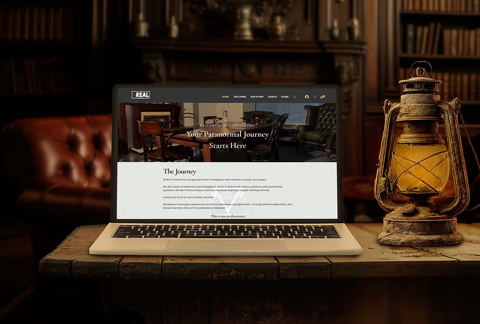 Laptop displaying "Your Paranormal Journey Starts Here" webpage on a wooden table with a glowing lantern, in a cozy library setting.