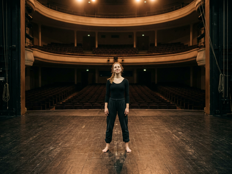 A dancer standing confidently on a theater stage, representing personal growth, self-confidence, and the importance of embracing your own dance journey.