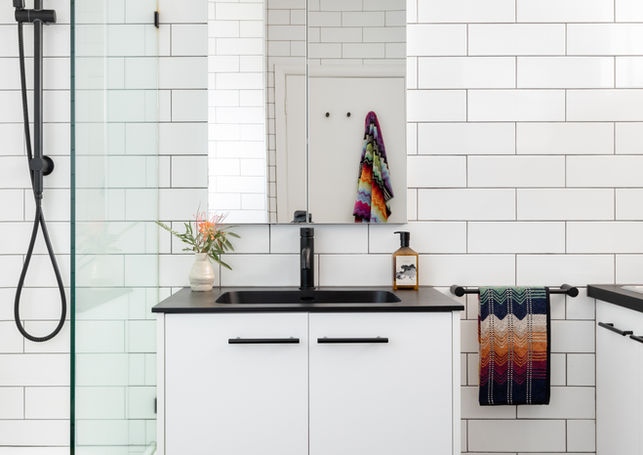 a bathroom with white tiles and a black sink