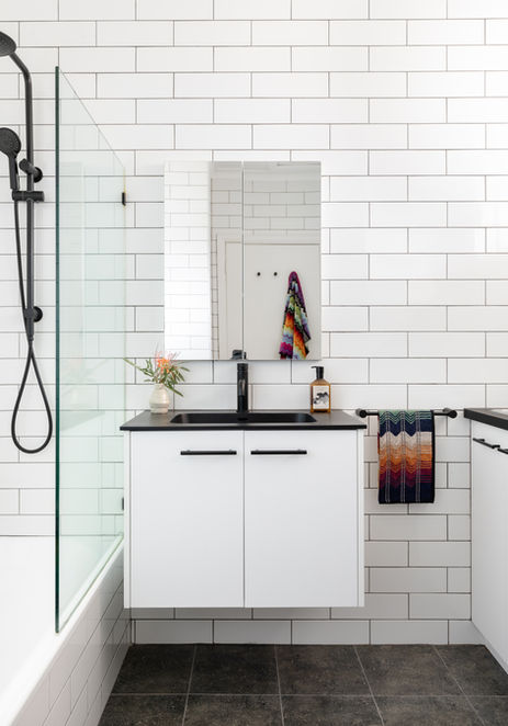 a bathroom with white tiles and a black sink