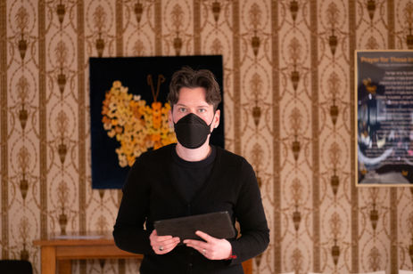 a man wearing a black face mask holds a tablet