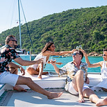 Group of man and woman friends enjoy party drinking champagne together while catamaran boa