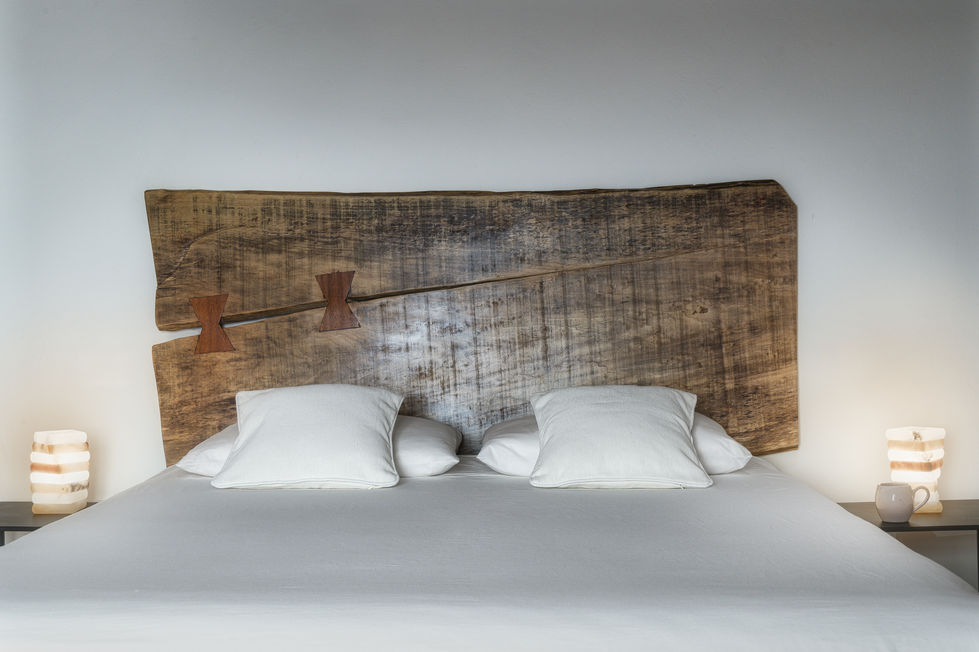 Bedroom with live-edge reclaimed wood headboard secured by butterfly keys, white bedding, and warm bedside lamps, Appartamento Montepulciano, Tuscany