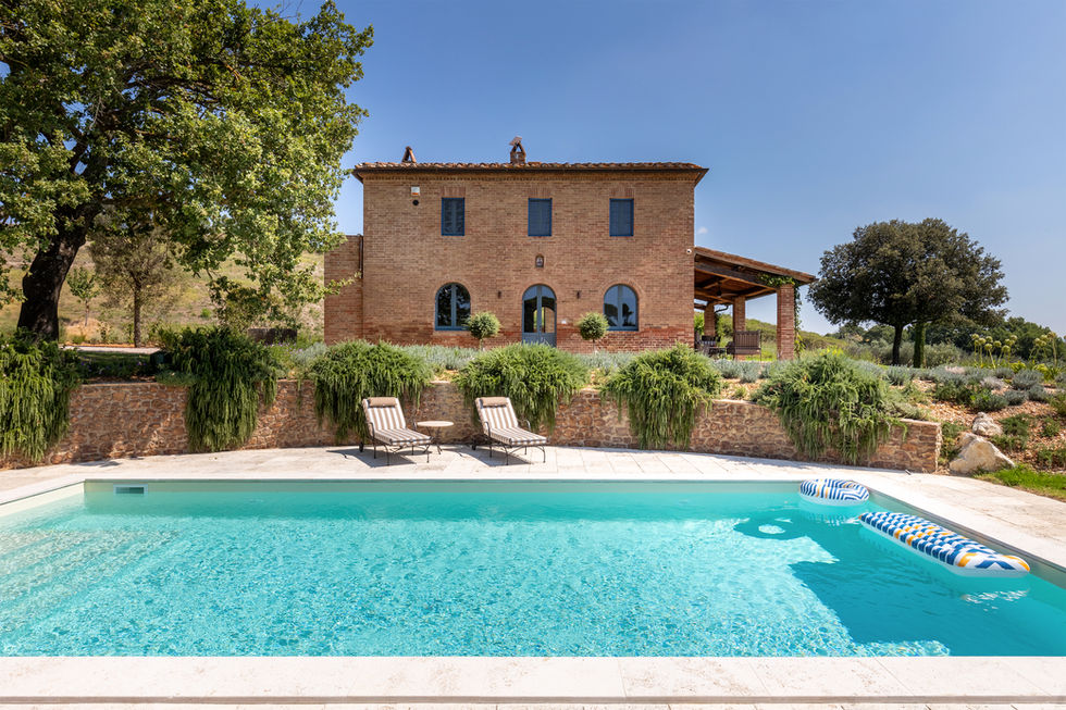 Stone and brick farmhouse with tiled roof, outdoor pool, terraced garden, and rolling Tuscan hills at Il Poderino, Montalcino