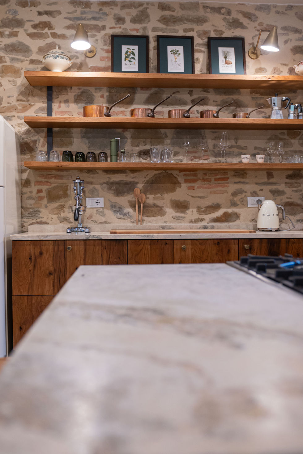 Kitchen detail with reclaimed wood cabinets, marble countertop, and exposed stone wall in Historic Farmhouse, Siena, Tuscany