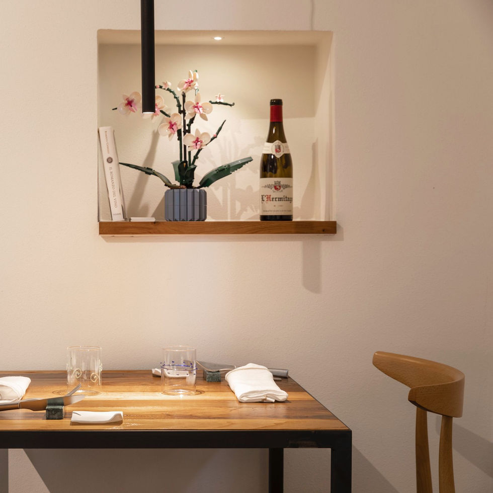 Osteria Foro dining table detail in Civitella in Val di Chiana, oak shelf with wine bottle and orchid in white plaster wall niche