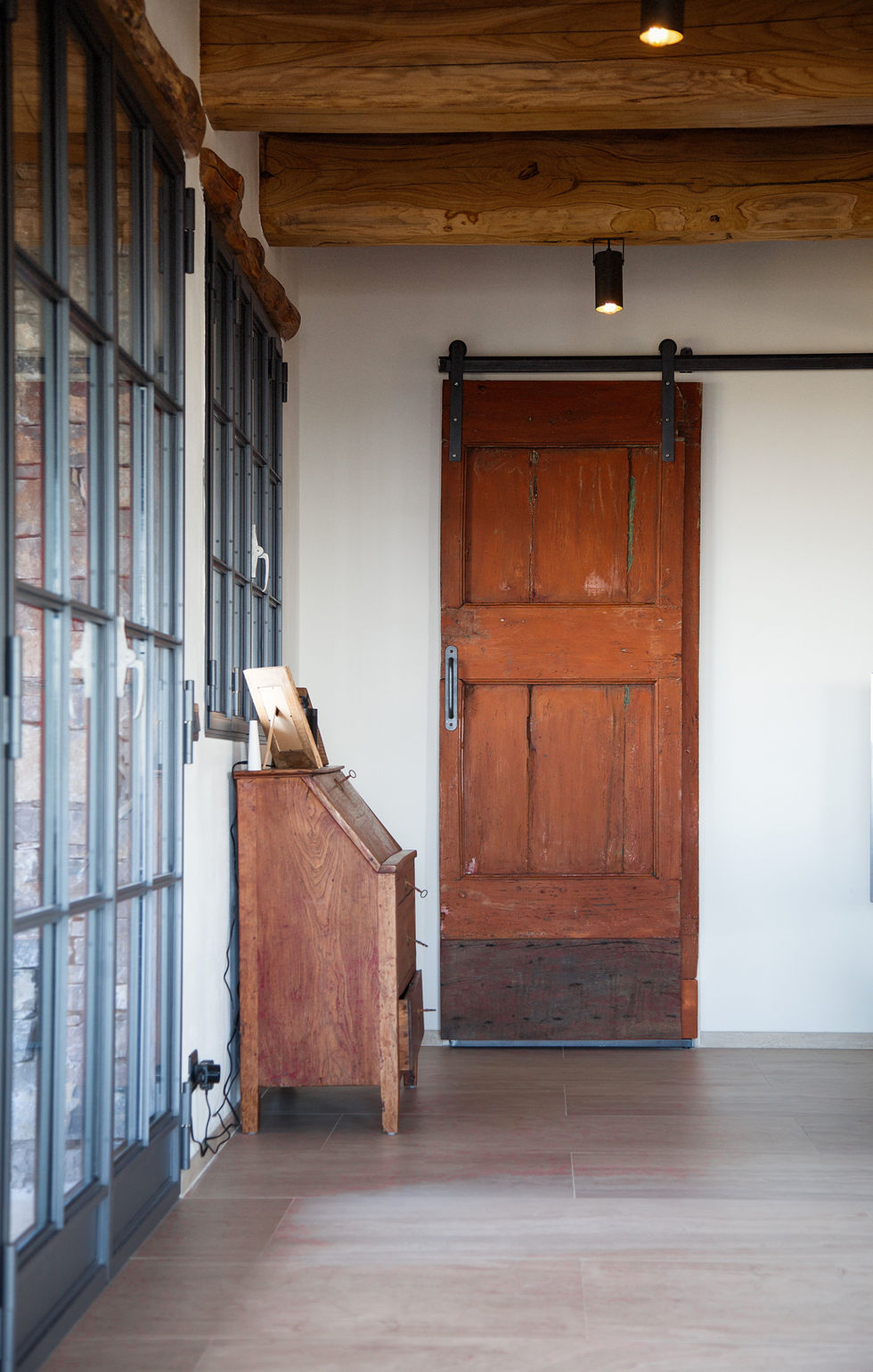 Entrance with aged red wooden barn door, iron-barred window, and rustic lectern, Villa Bel Colle, Scansano, Maremma, Tuscany