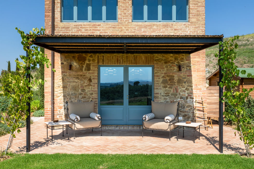 Covered terrace with steel pergola, terracotta brick paving, and two lounge chairs at Il Poderino, Montalcino, Tuscany