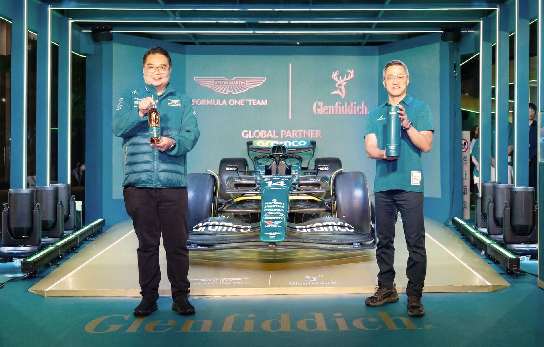 兩位男士在F1賽車前的展覽設計，展示品牌。