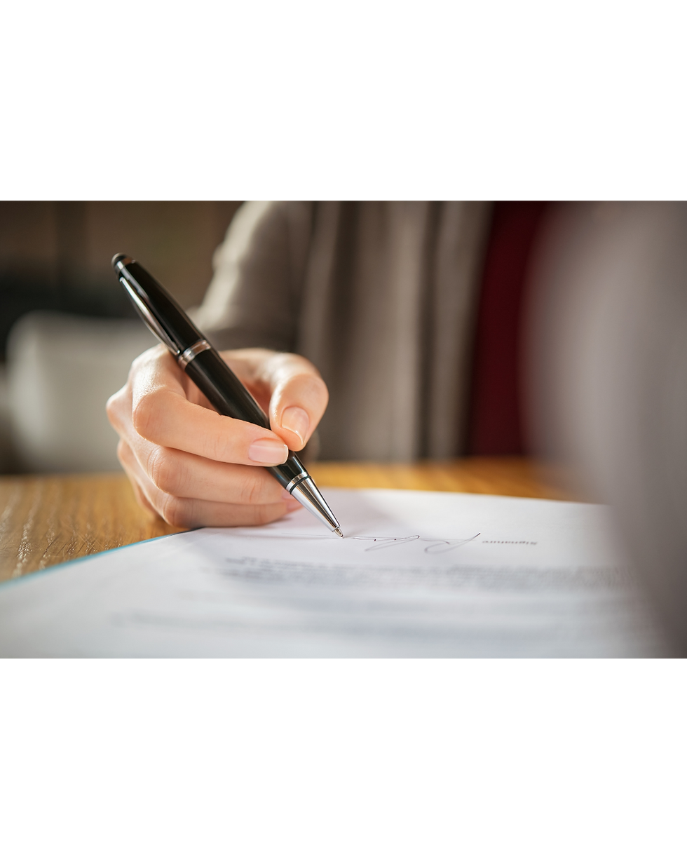 Persona firmando un poder notarial en escritura pública ante notario