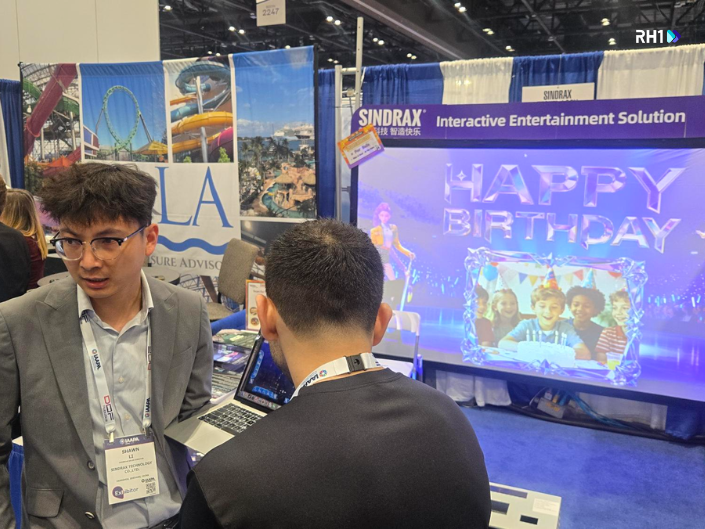Two people standing in front of a motion-based LED game at IAAPA Expo 2025, showing interactive and immersive gameplay