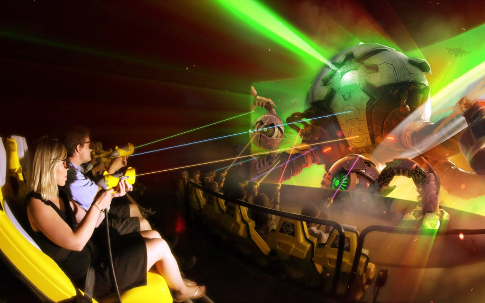 Riders aiming blasters at a giant robot enemy in an interactive dark ride experience